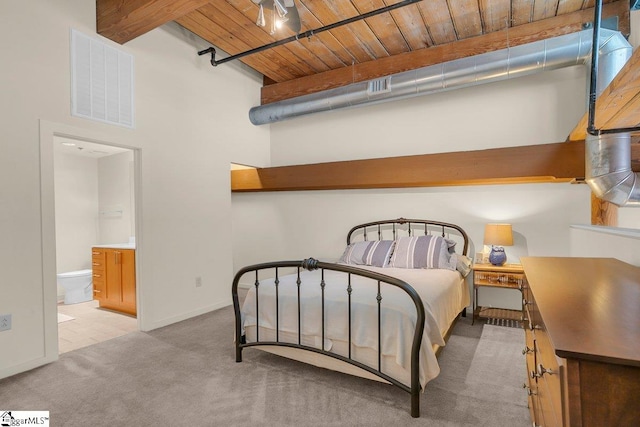 bedroom featuring wooden ceiling, beamed ceiling, connected bathroom, a high ceiling, and light colored carpet