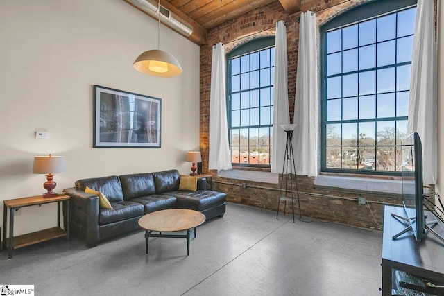 living room with brick wall, concrete flooring, and beam ceiling