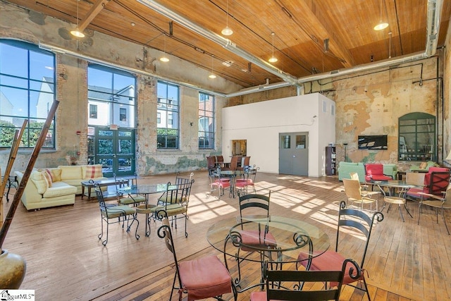 dining area featuring a high ceiling, a healthy amount of sunlight, and hardwood / wood-style flooring