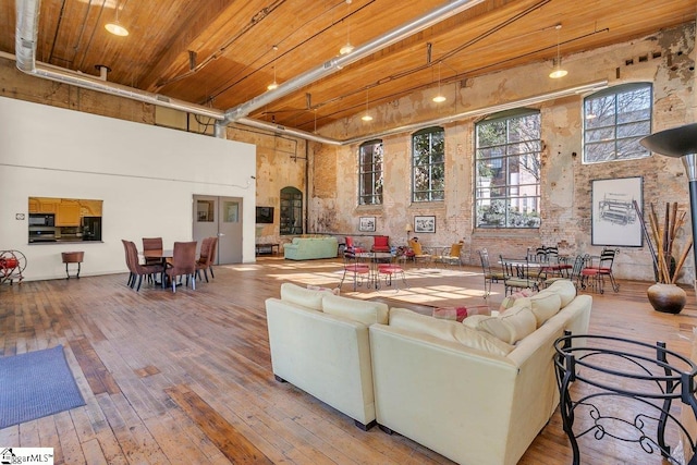 living room featuring a towering ceiling, hardwood / wood-style flooring, and wooden ceiling