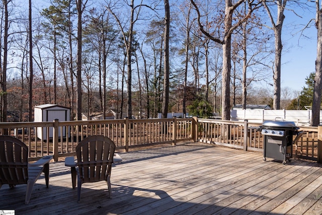 wooden deck featuring a shed and area for grilling