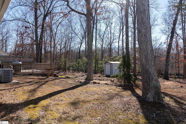 view of yard featuring a wooden deck, cooling unit, and a storage unit