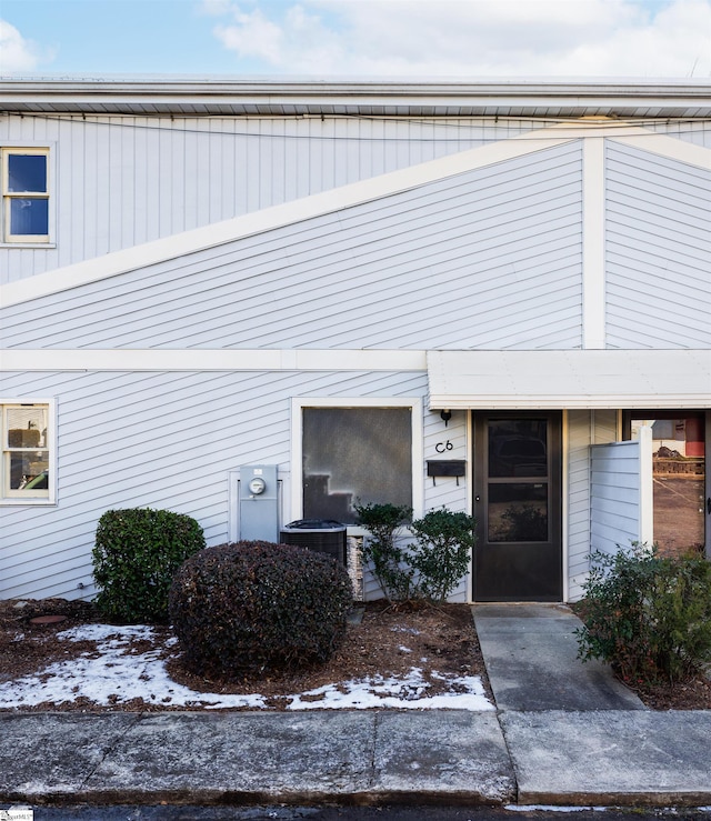 snow covered property entrance with cooling unit