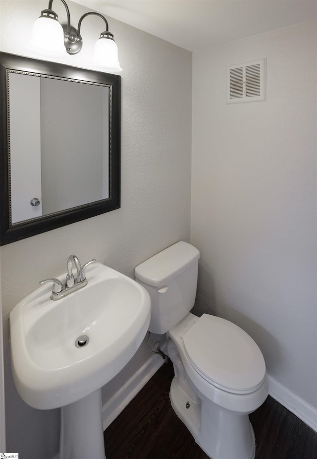 bathroom with toilet, wood-type flooring, and sink