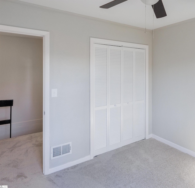 unfurnished bedroom with a closet, ceiling fan, ornamental molding, and light colored carpet