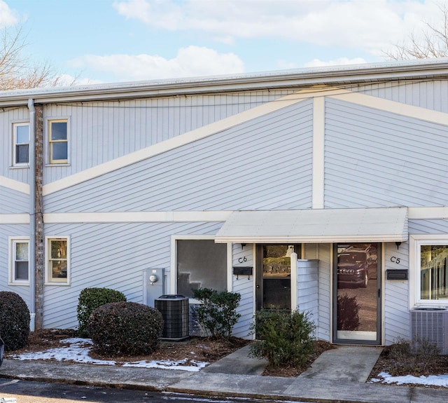 snow covered property entrance with cooling unit