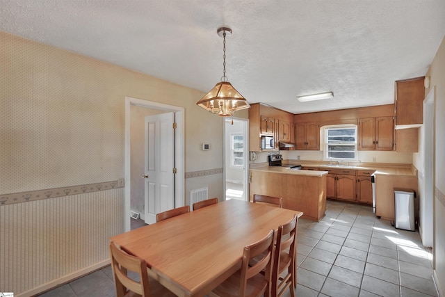 tiled dining area with a textured ceiling, a chandelier, and sink