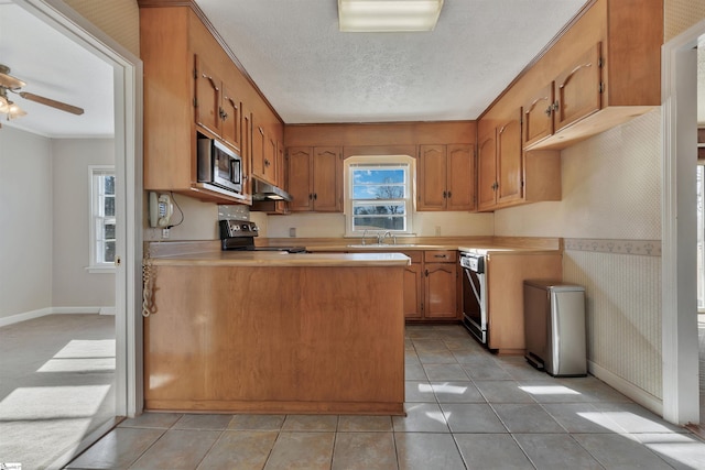 kitchen featuring appliances with stainless steel finishes, kitchen peninsula, ceiling fan, a textured ceiling, and sink