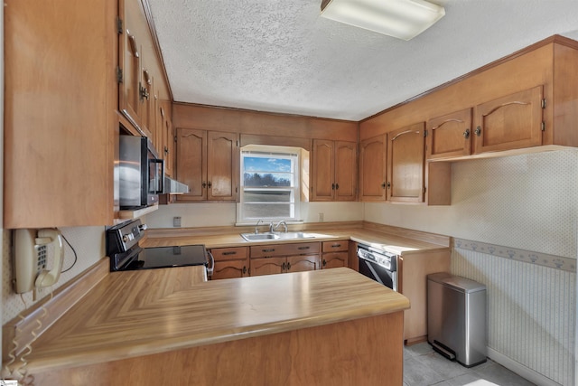 kitchen with sink, a textured ceiling, light tile patterned floors, kitchen peninsula, and appliances with stainless steel finishes