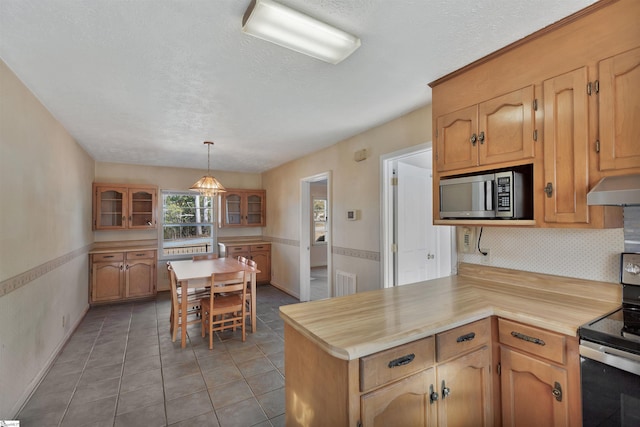 kitchen with pendant lighting, butcher block countertops, backsplash, appliances with stainless steel finishes, and light tile patterned flooring