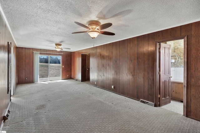 interior space featuring wood walls, ceiling fan, and light colored carpet