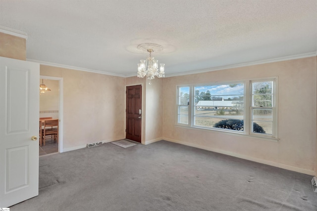 carpeted spare room featuring an inviting chandelier, ornamental molding, and a textured ceiling