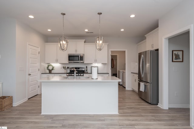 kitchen featuring decorative light fixtures, an island with sink, appliances with stainless steel finishes, and white cabinets