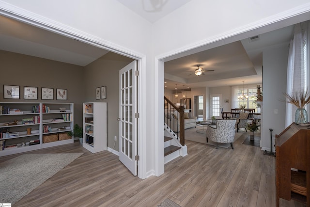 interior space featuring a tray ceiling, a chandelier, and wood-type flooring