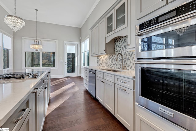 kitchen featuring light stone counters, decorative light fixtures, dark hardwood / wood-style flooring, appliances with stainless steel finishes, and sink