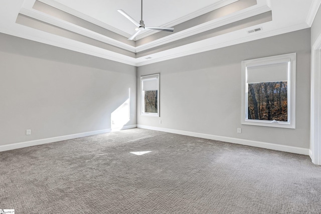 unfurnished room featuring a raised ceiling, carpet, ornamental molding, and ceiling fan