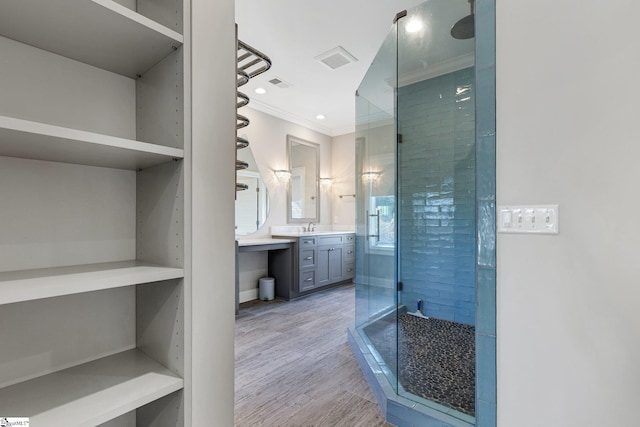 bathroom with ornamental molding, a shower with door, hardwood / wood-style floors, and vanity