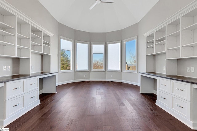 unfurnished office with built in desk, dark hardwood / wood-style flooring, high vaulted ceiling, and ceiling fan