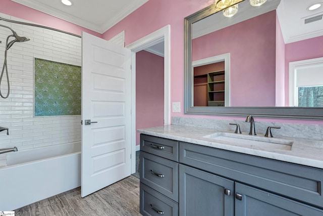 bathroom with tiled shower / bath combo, crown molding, wood-type flooring, and vanity