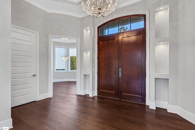 entrance foyer with dark hardwood / wood-style flooring, an inviting chandelier, and ornamental molding