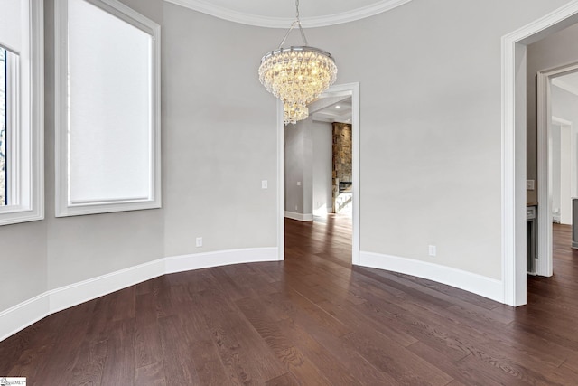 unfurnished dining area featuring an inviting chandelier, crown molding, and dark hardwood / wood-style flooring