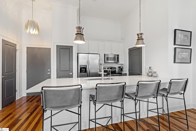 kitchen featuring a breakfast bar area, appliances with stainless steel finishes, kitchen peninsula, ornamental molding, and white cabinetry