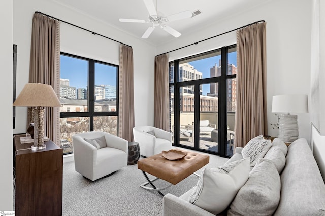 living room featuring ornamental molding, ceiling fan, and carpet