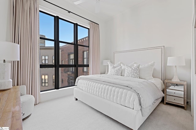 bedroom featuring ornamental molding, ceiling fan, light carpet, and multiple windows