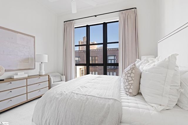 bedroom with ceiling fan, beam ceiling, crown molding, and light colored carpet