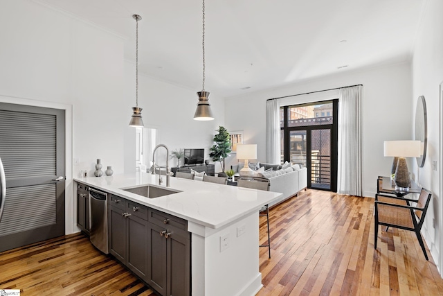 kitchen with sink, light stone counters, light wood-type flooring, kitchen peninsula, and stainless steel dishwasher