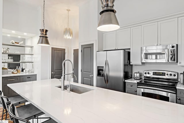 kitchen featuring light stone counters, stainless steel appliances, gray cabinetry, and sink