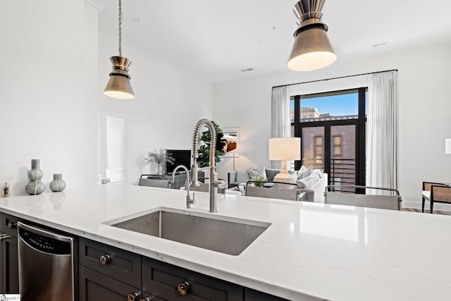 kitchen with light stone counters, dishwasher, pendant lighting, and sink