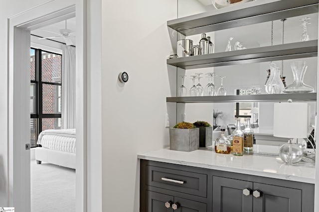 bar featuring gray cabinetry and light stone counters