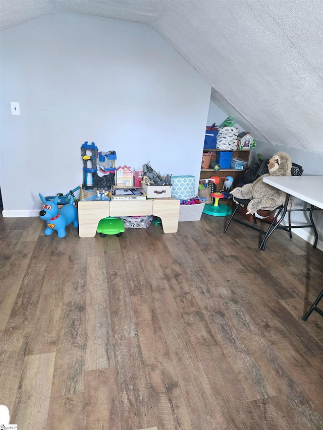 additional living space with a textured ceiling, vaulted ceiling, and dark hardwood / wood-style floors