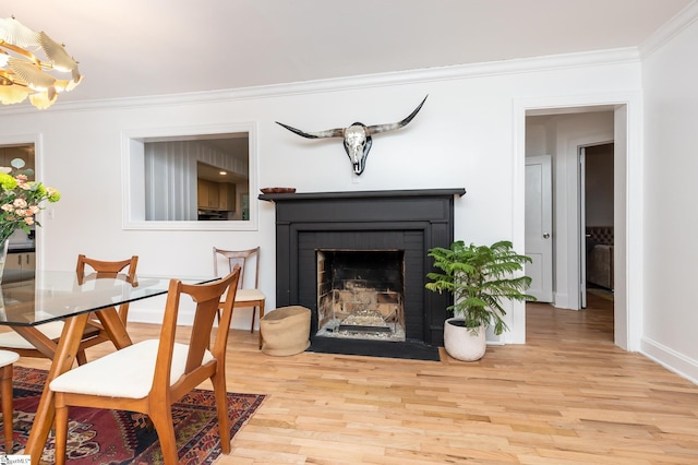 sitting room featuring wood-type flooring, a brick fireplace, and ornamental molding