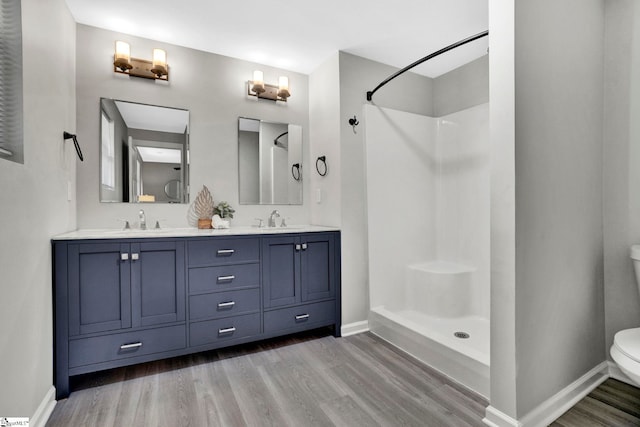 bathroom featuring toilet, hardwood / wood-style flooring, a shower, and vanity