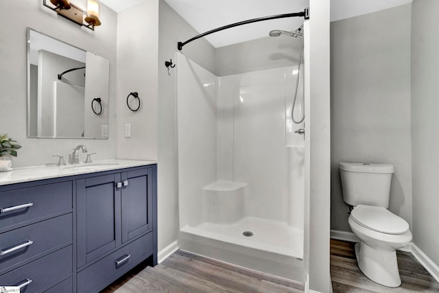 bathroom with walk in shower, hardwood / wood-style floors, vanity, and toilet