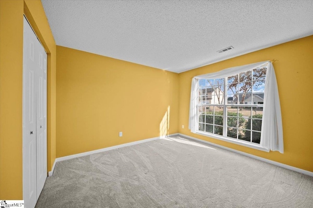 empty room featuring a textured ceiling and carpet