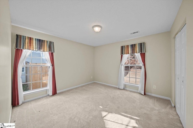 empty room with a textured ceiling and light carpet