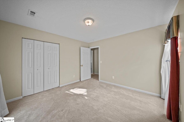 unfurnished bedroom featuring light colored carpet, a closet, and a textured ceiling