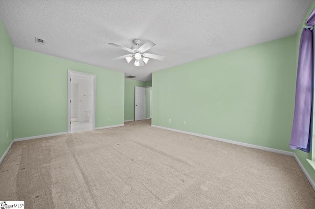 unfurnished bedroom with ceiling fan, connected bathroom, carpet floors, and a textured ceiling