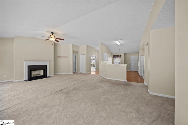 unfurnished living room with lofted ceiling, a textured ceiling, ceiling fan, and light carpet