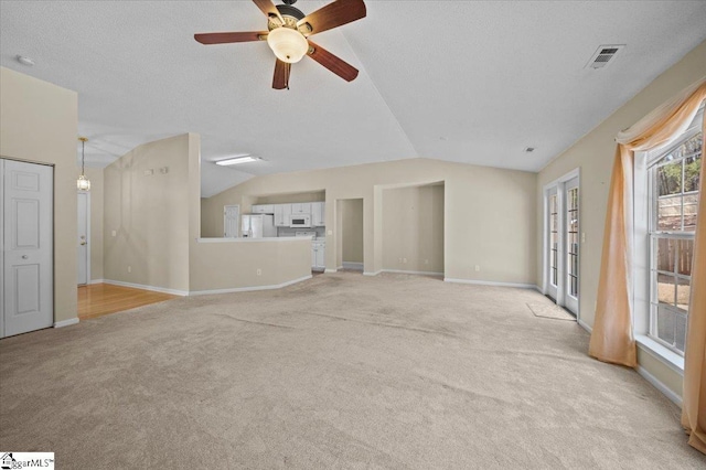 unfurnished living room featuring lofted ceiling, a textured ceiling, ceiling fan, and light carpet