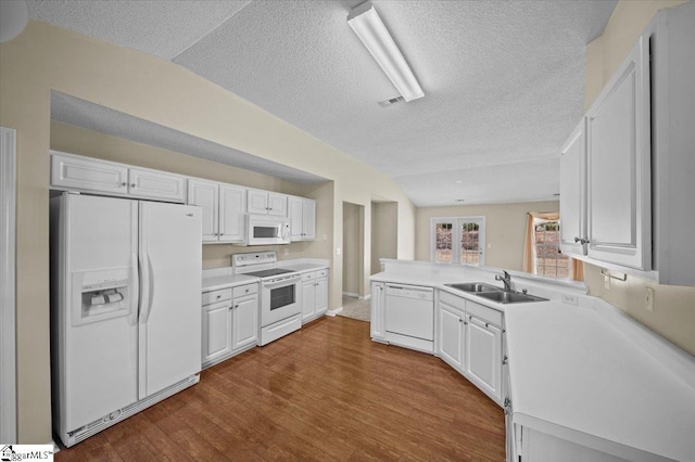 kitchen with white appliances, white cabinets, lofted ceiling, and sink