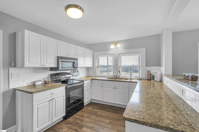 kitchen with electric range, kitchen peninsula, decorative backsplash, sink, and white cabinetry