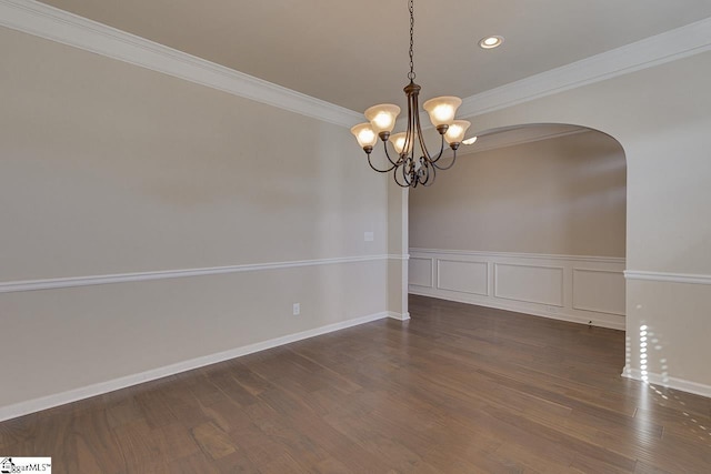 unfurnished room with ornamental molding, dark wood-type flooring, and an inviting chandelier