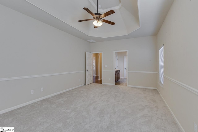 unfurnished bedroom featuring ceiling fan, light colored carpet, and a raised ceiling