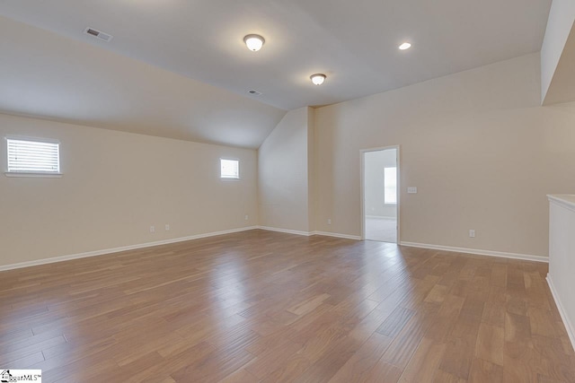 empty room featuring light wood-type flooring and vaulted ceiling