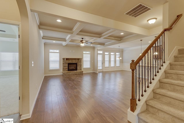 unfurnished living room featuring a fireplace, ornamental molding, ceiling fan, coffered ceiling, and beam ceiling