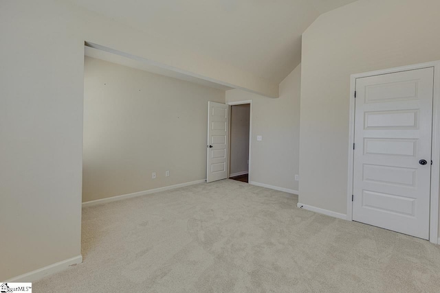 spare room featuring lofted ceiling and light colored carpet